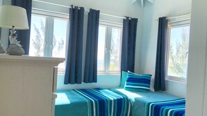 Ein Zimmer mit zwei Betten, einer Lampe und Vorhängen.