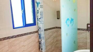 A bathroom with a shower, a sink, and a window.