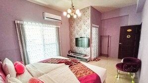Un dormitorio con cama, televisor, aire acondicionado, silla y puerta.