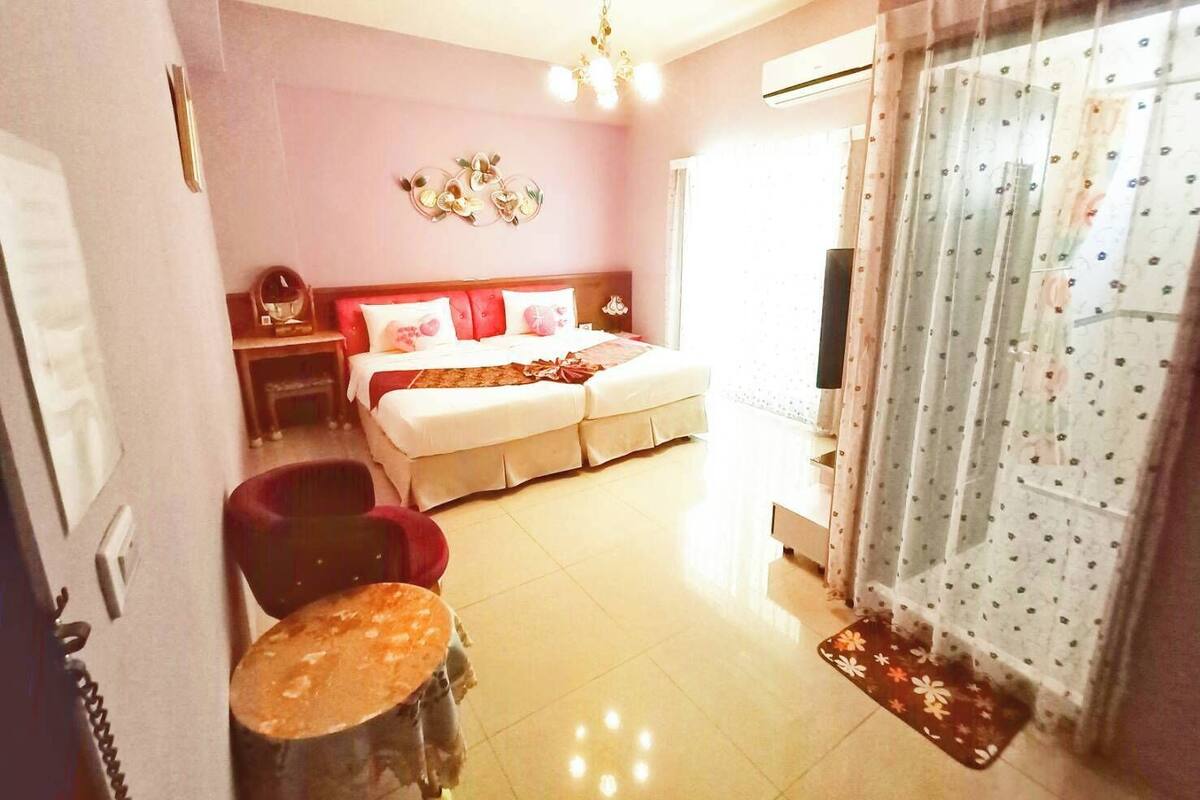 A hotel room with a bed, a desk, a chair, and a small table.