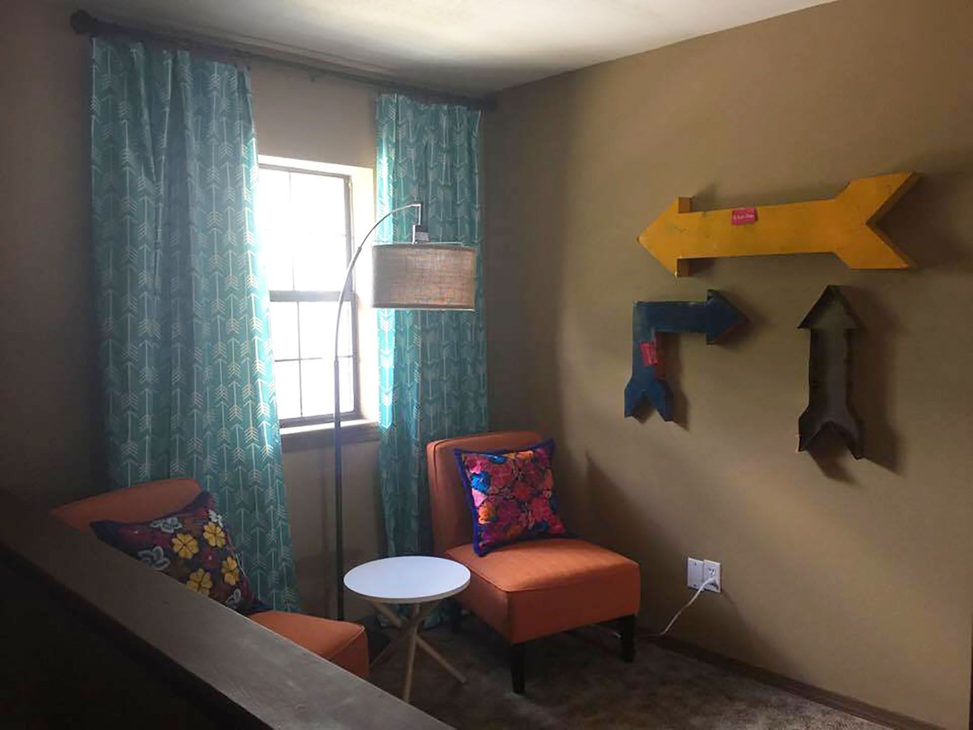 A room with a window, a chair, a small table, and directional arrows on the wall.