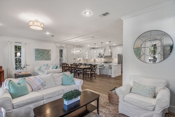 A modern living room with a sofa, coffee table, and a dining area with chairs and a table.