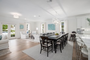 A spacious living area with a dining table, chairs, and a kitchen area with a bar.
