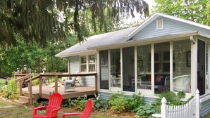 Une maison avec un porche couvert, une terrasse et une cour clôturée.