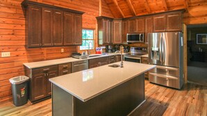 Cocina moderna con paredes de madera, electrodomésticos de acero inoxidable y una isla central.
