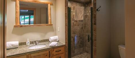 A bathroom with a wooden vanity, a glass-enclosed shower, and a toilet.
