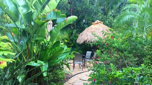 Un sendero en un jardín con una estructura de techo de paja y asientos al aire libre.
