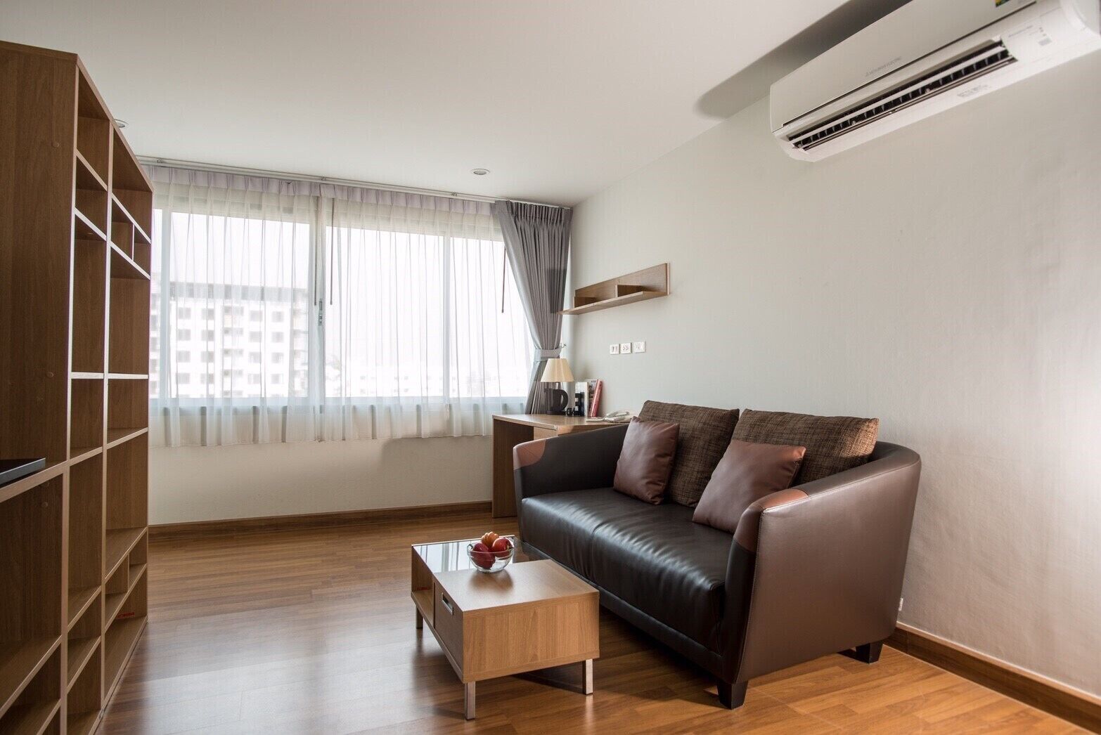 A modern living room with a leather sofa, a wooden coffee table, and a built-in bookshelf.