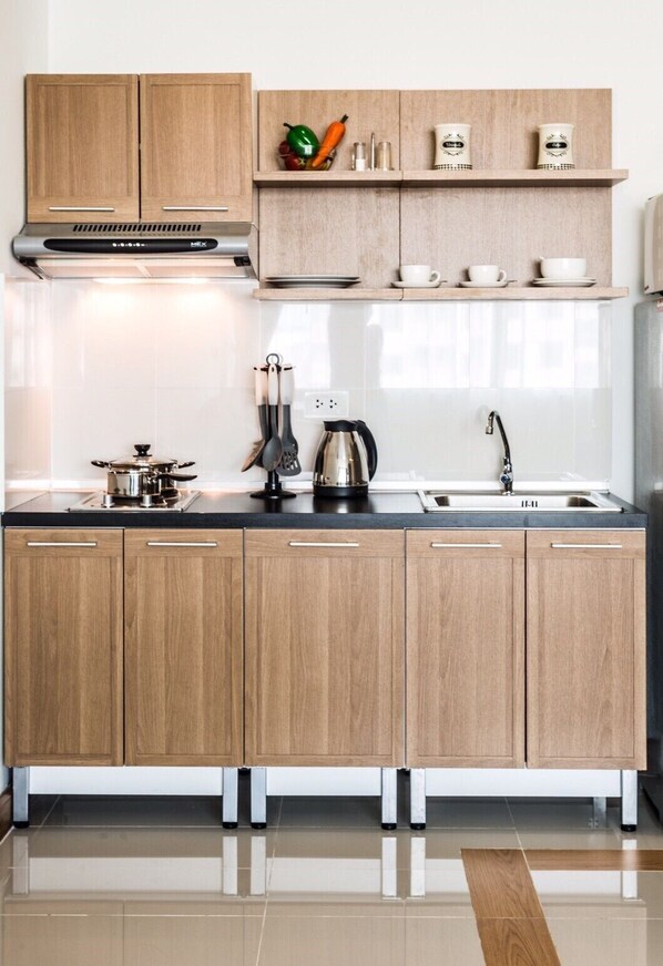 A modern kitchen with wooden cabinets, a stainless steel range hood, a coffee maker, and a sink. - Winner Prachinburi & Serviced Apartment (Si Maha Phot)