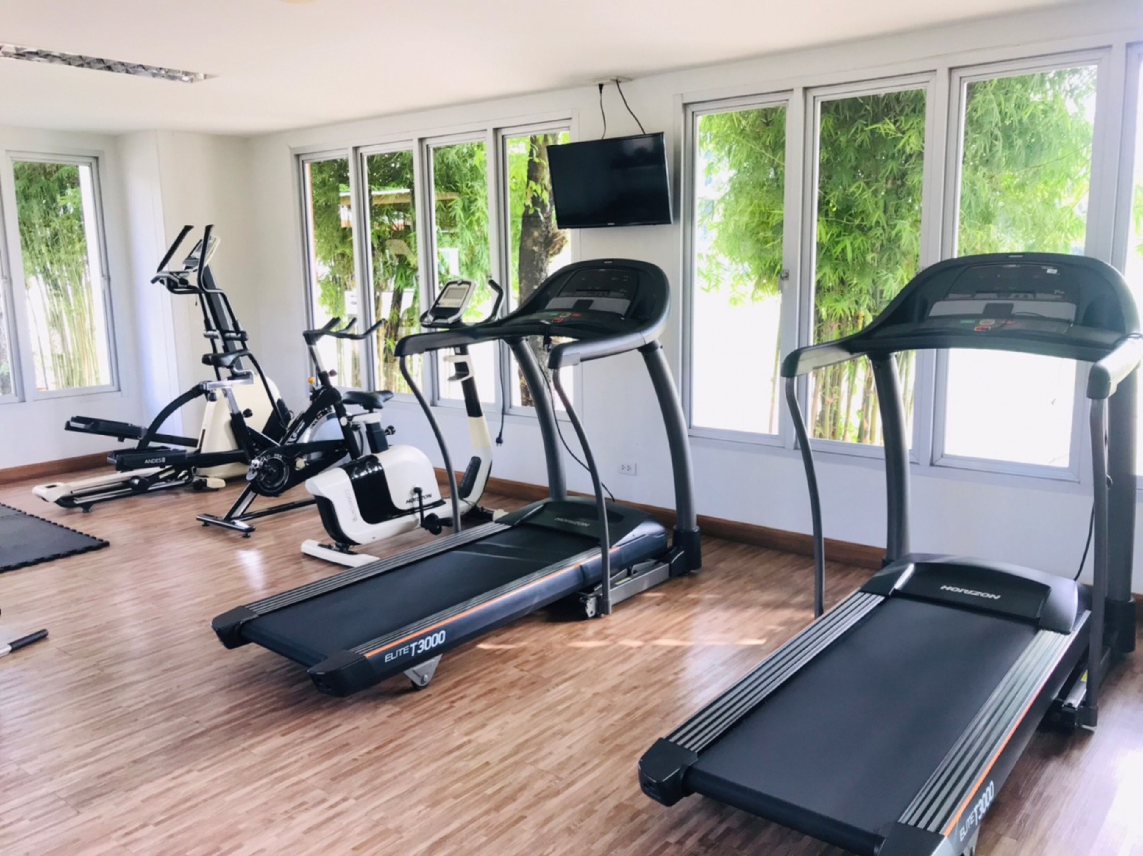 Une salle de sport équipée de tapis de course, de vélos d’appartement et d’appareils elliptiques.