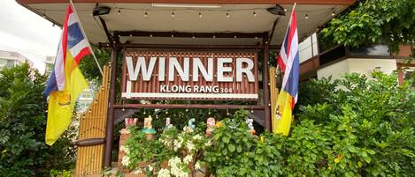 A sign reading "WINNER KLONG RANG 304" with flags and decorative elements.