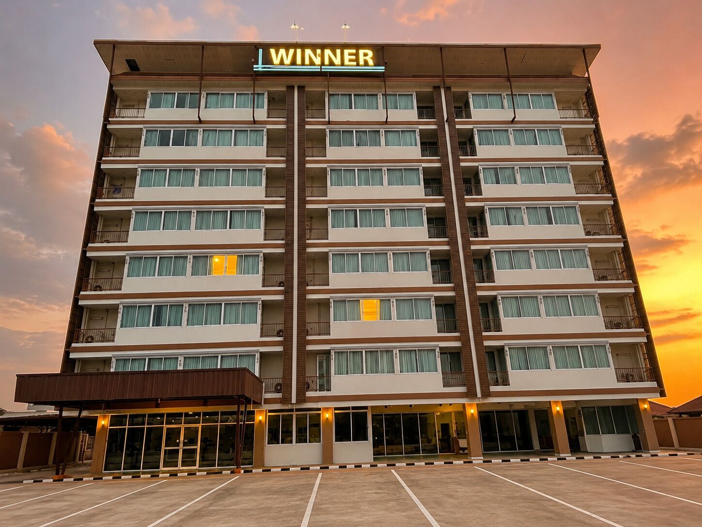 A multi-story hotel with a prominent 'WINNER' sign, a covered entrance, and a parking lot.