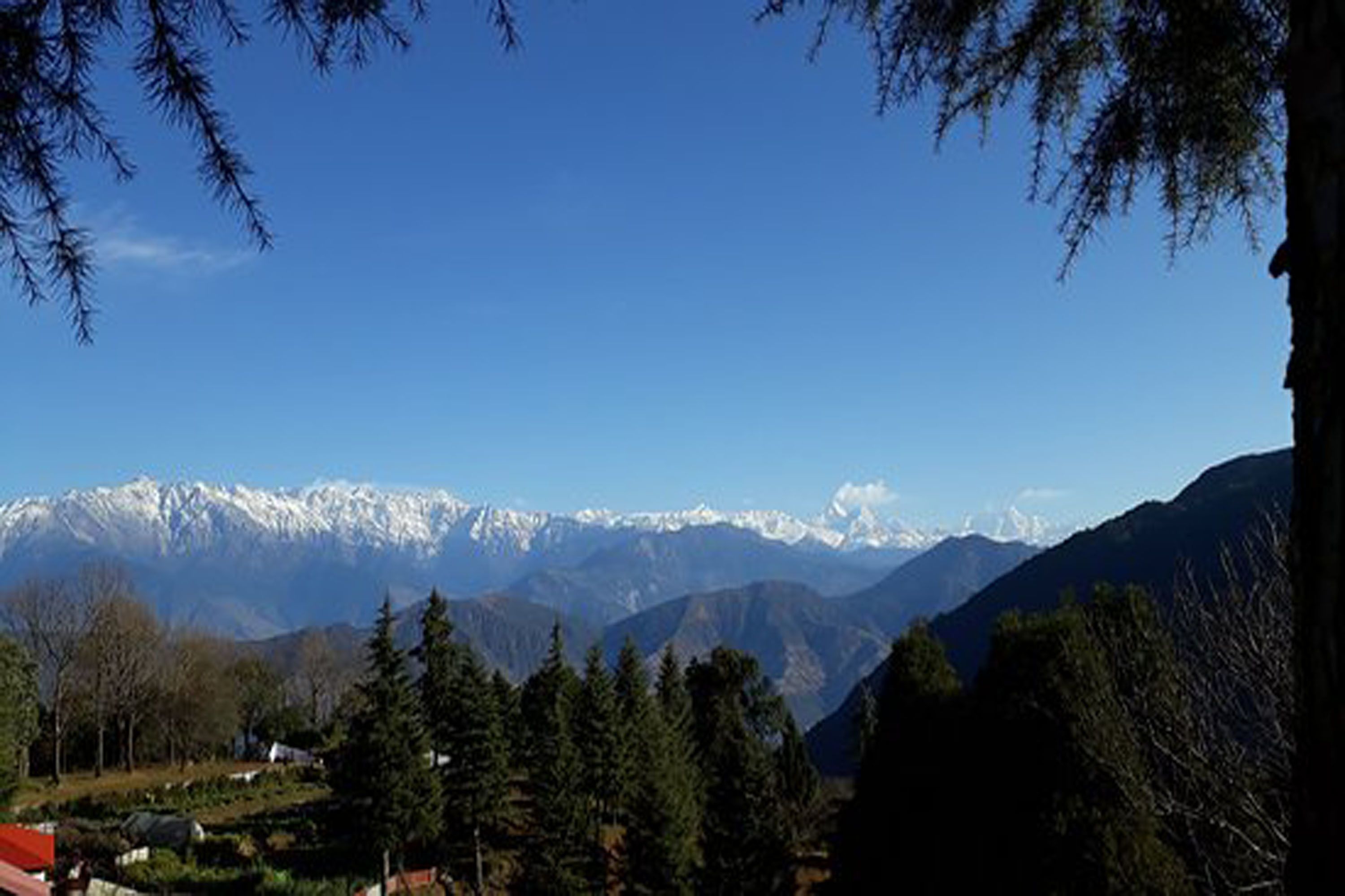Un paysage montagneux aux sommets enneigés, sous un ciel bleu dégagé.