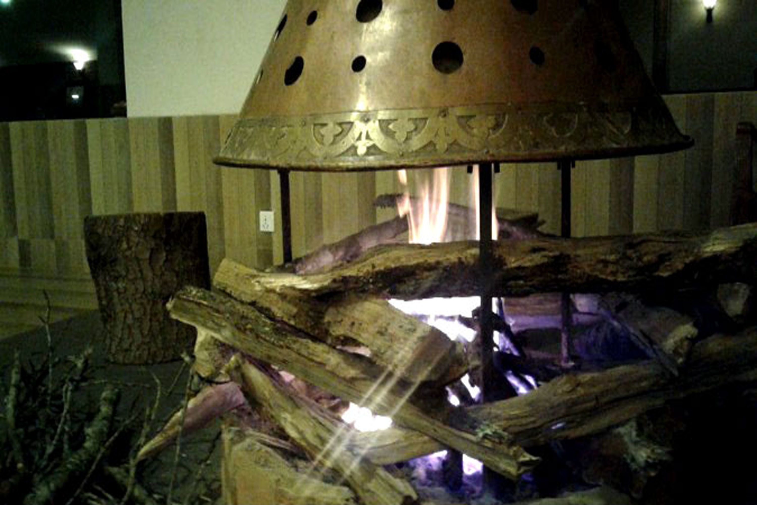 Una fogata con leña y una tapa metálica decorativa.