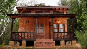 A rustic wooden cabin with a porch, a door, and windows. - Chhaimale Resort (Dakshinkali)