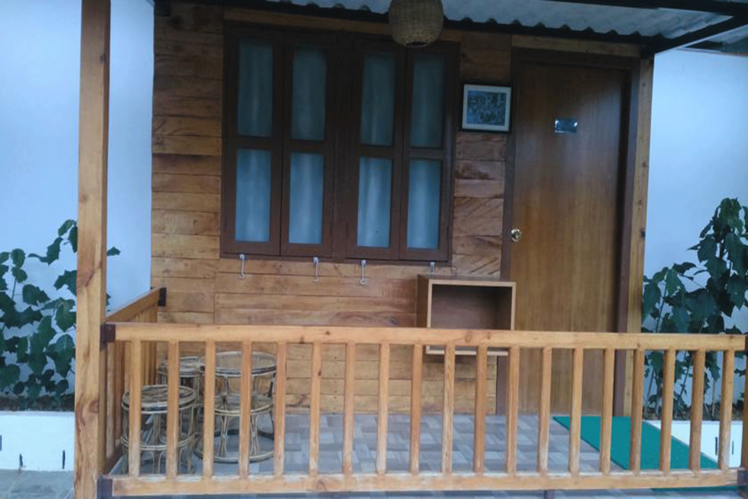Uma casa de madeira com varanda, porta e janela.