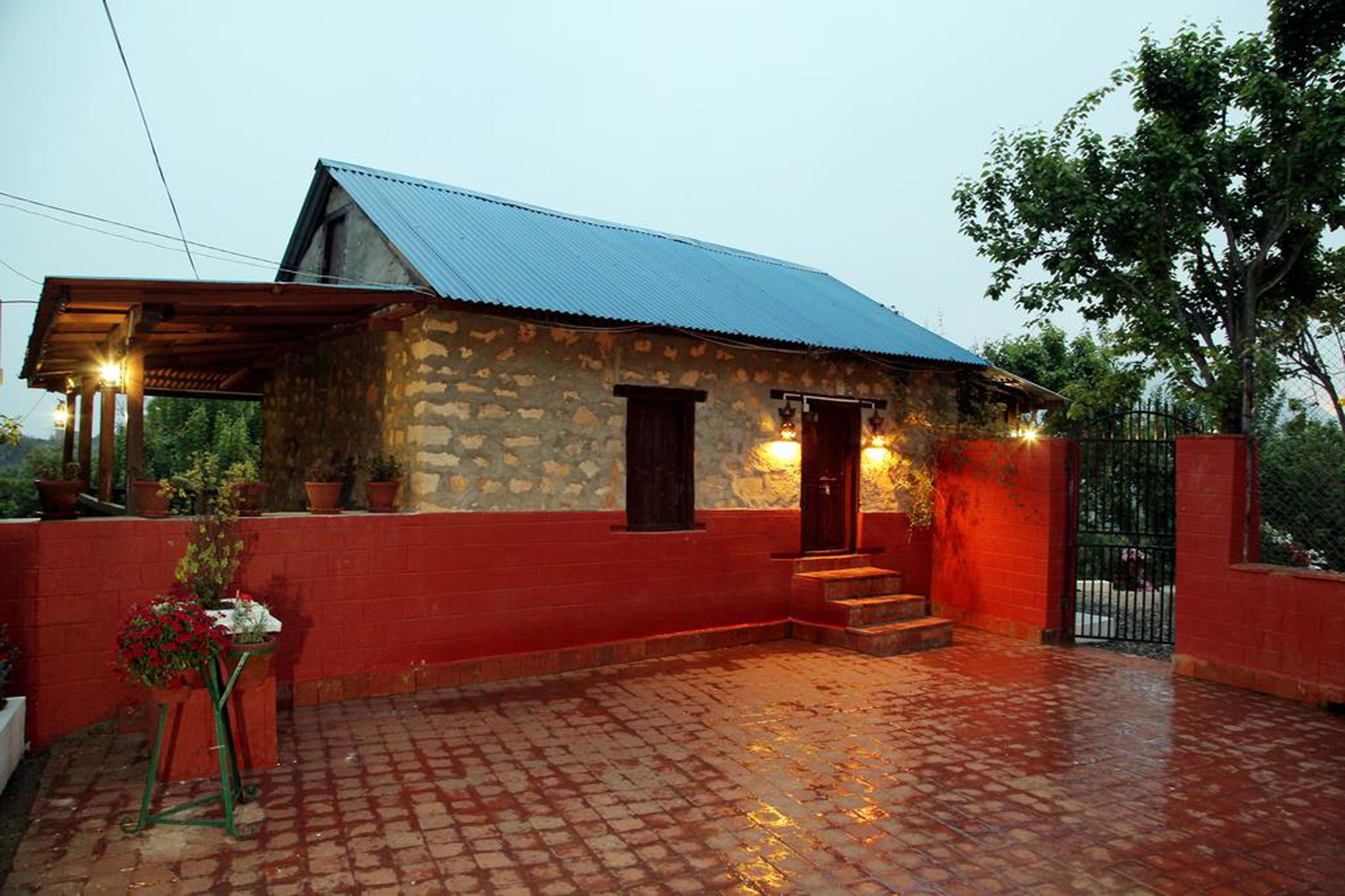 A stone building with a red exterior and a blue roof, featuring a small porch and steps leading to the entrance.