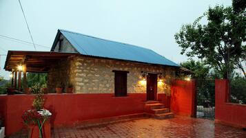 A stone building with a red exterior and a blue roof, featuring a small porch and steps leading to the entrance.