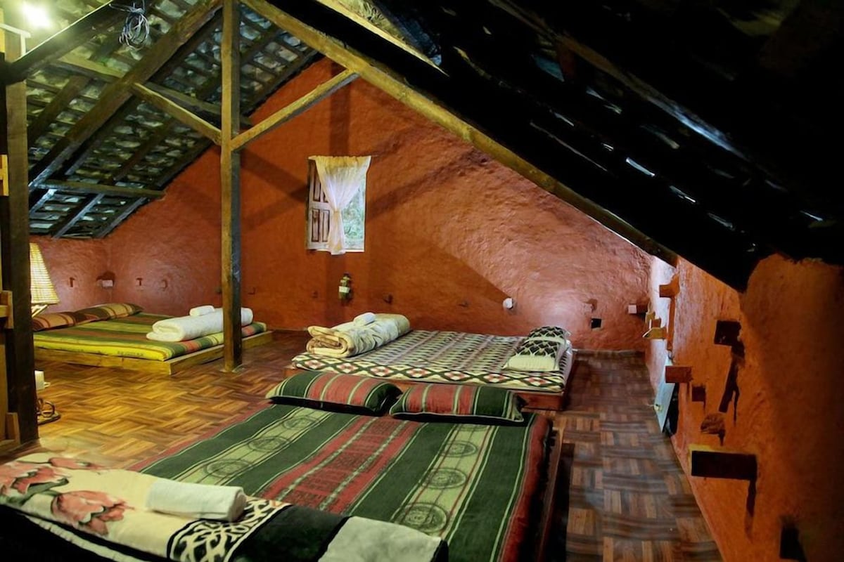 A rustic attic bedroom with a sloped ceiling, wooden beams, and a single bed with a patterned bedspread.