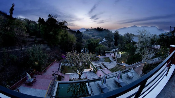 A terrace with outdoor seating and a view of a mountainous landscape. - Chhaimale Resort (Dakshinkali)