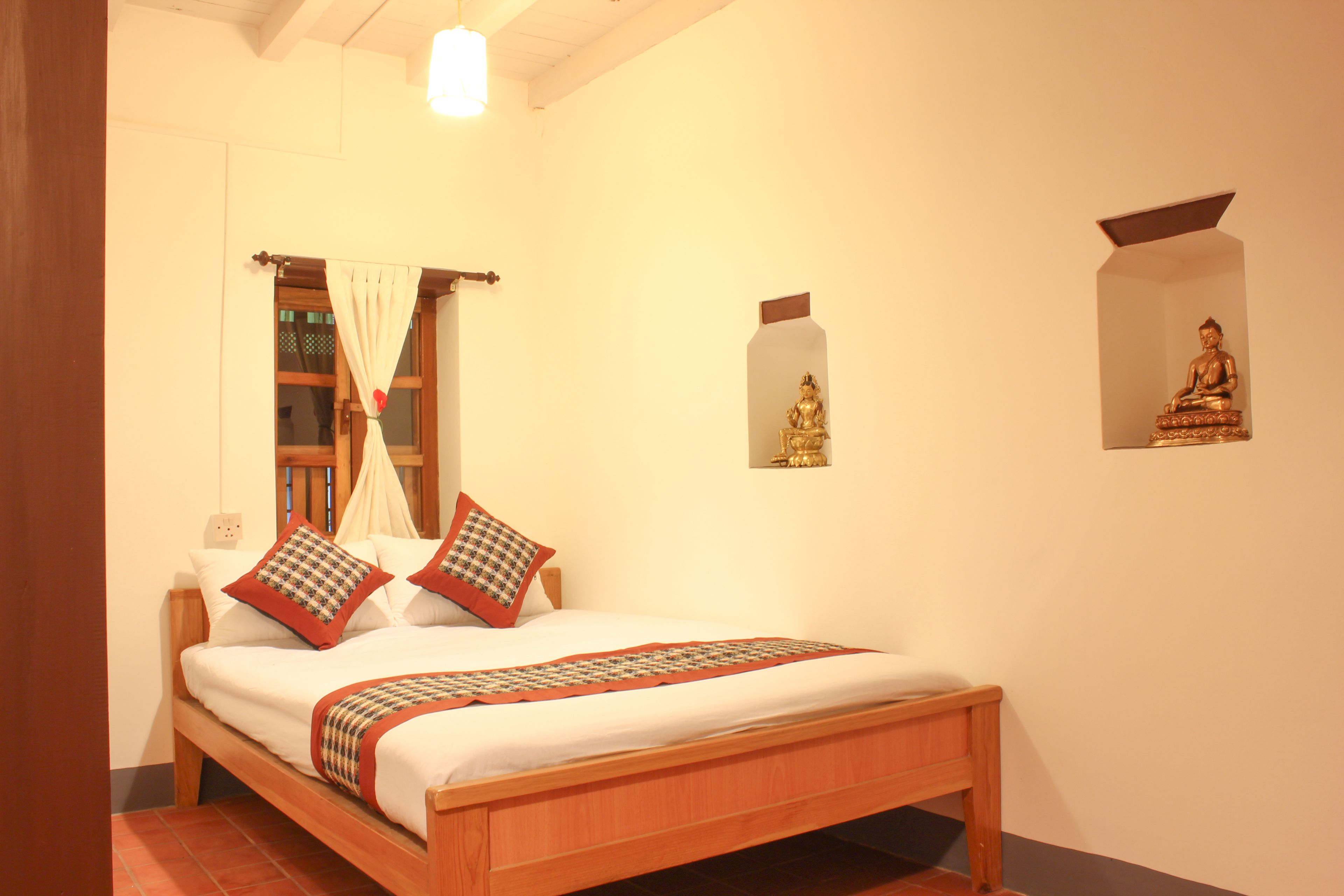 A wooden bed with a white mattress, two pillows, and a patterned blanket.