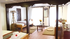 A room with two beds, a wooden bench, a small table, and a decorative lamp. - Hiranya Guest House (Lalitpur)