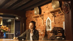 A rustic room with exposed brick walls, wooden beams, and a traditional stove. - Hiranya Guest House (Lalitpur)