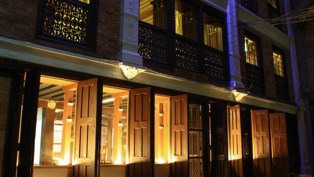 A building with multiple open wooden doors and windows, suggesting a commercial establishment. - Hiranya Guest House (Lalitpur)