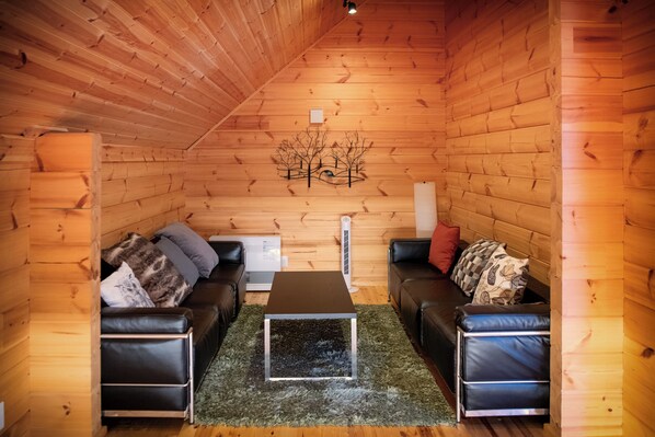 A cozy log cabin interior with two leather sofas, a central table, and a decorative wall piece.