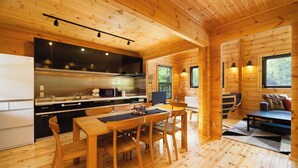 A wooden cabin interior with a kitchen, dining area, and living space. - Wadano Woods Chalet (Hakuba)
