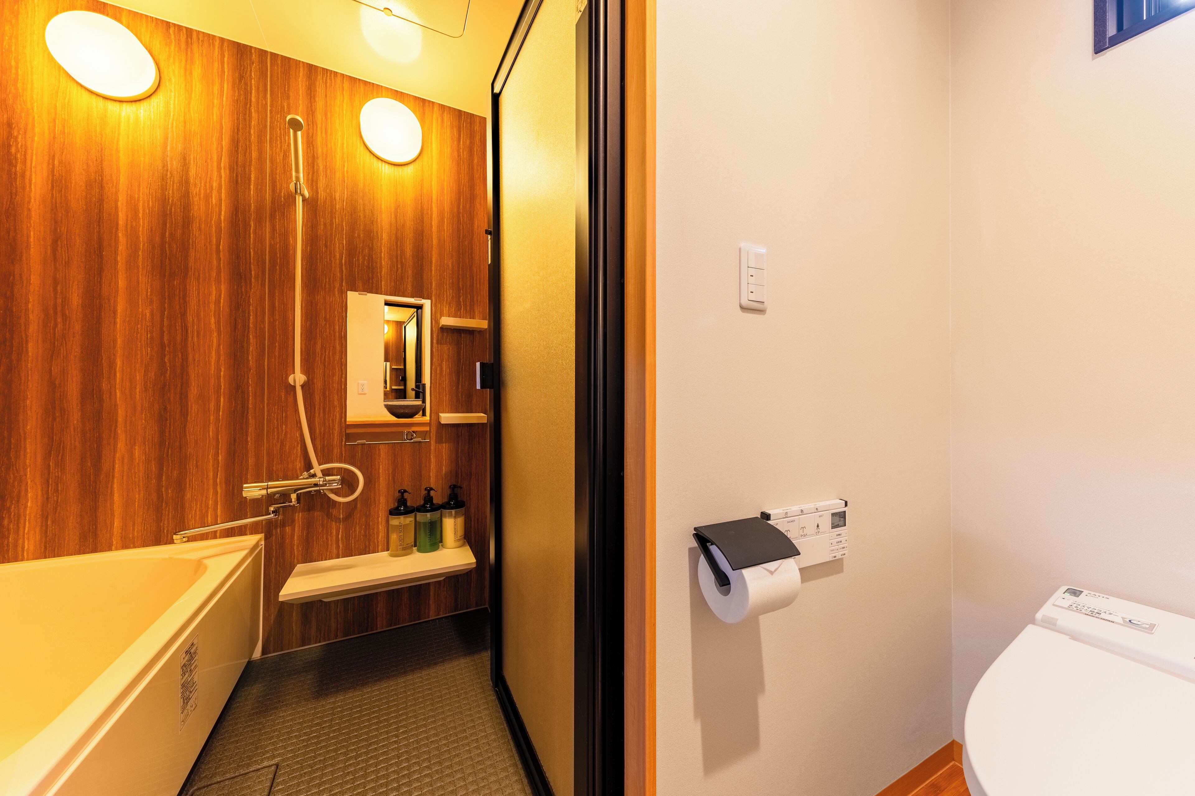 A bathroom with a wooden vanity, a bathtub, a toilet, and a shower.