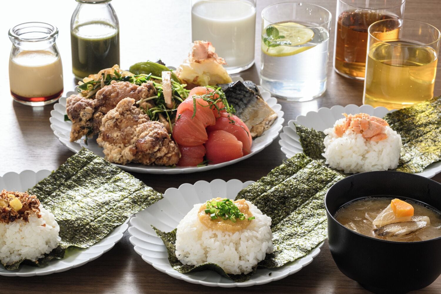 Variedad de platos japoneses, como sushi, sashimi y bowls de arroz, acompañados de bebidas y salsas.