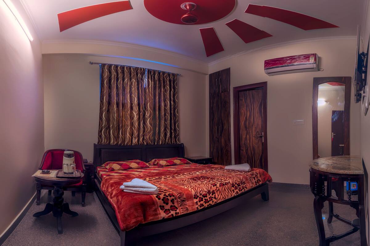 A bedroom with a bed, a desk, a chair, a wardrobe, and a ceiling fan.