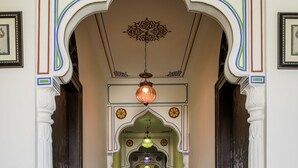 A corridor with ornate arches and a chandelier. - Kalyan Heritage (Jaipur)