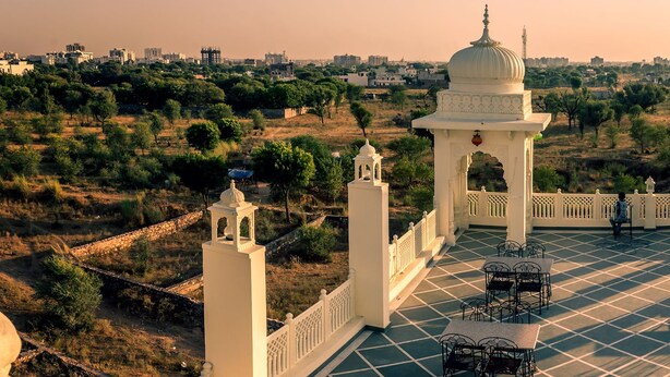 A courtyard with a central fountain, surrounded by white columns and arches, with a view of a cityscape in the background. - Kalyan Heritage (Jaipur)