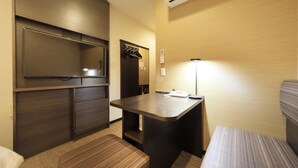 Habitación de hotel compacta con cama, un escritorio pequeño, un armario y un equipo de aire acondicionado.