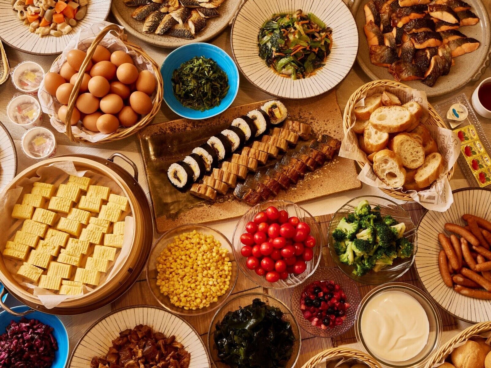 Una variedad de platos que incluyen sushi, maíz y verduras, lo que sugiere una amplia selección de comidas.