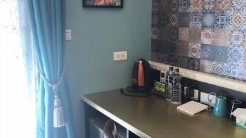 A room with a desk, a chair, a wall with patterned tiles, a painting, and a window with curtains.