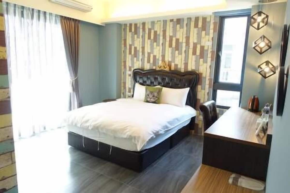 Un dormitorio ordenado con una cama, mesita de noche y una ventana con cortinas.