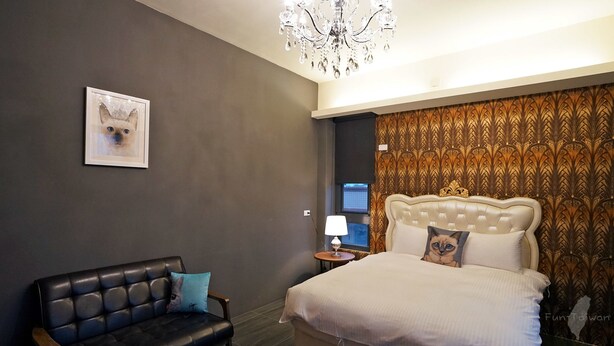 Una habitación de hotel moderna con un sofá de cuero, una cama grande con cabecera acolchada, una araña y papel tapiz estampado.