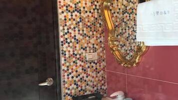 A bathroom with a mosaic tile wall, a gold-framed mirror, a white sink, and a dark door.