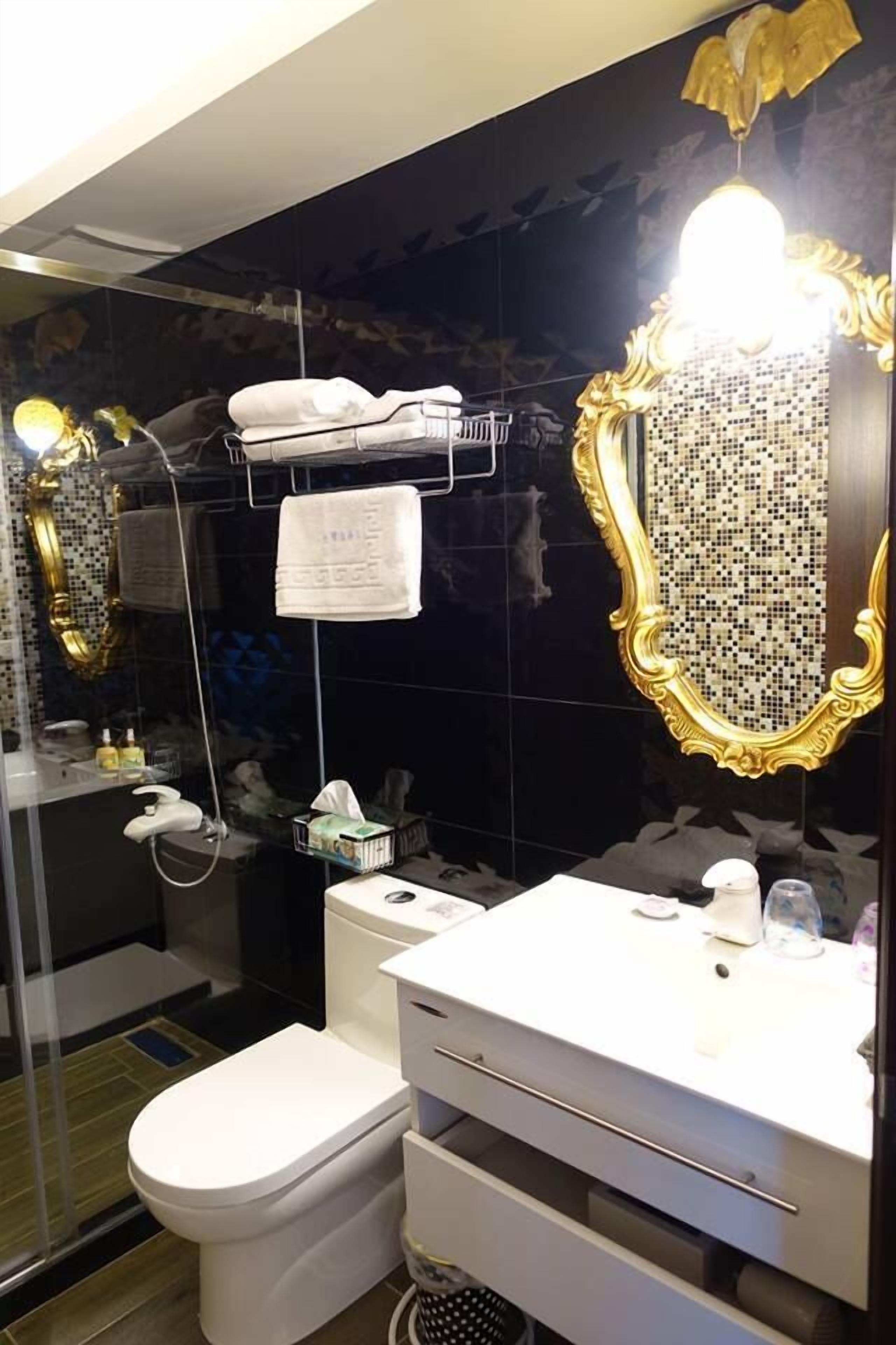 A modern bathroom with a white toilet, a white sink with a mirror, and a shower area.