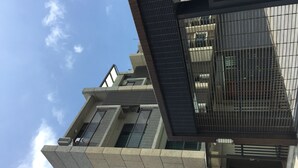 Un edificio moderno con una combinación de fachadas de vidrio y concreto, que presenta un llamativo letrero con forma de gato y una escalera visible.