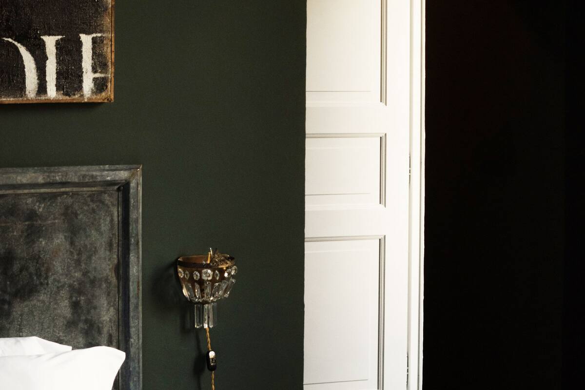 Una habitación con una cama, una mesita y una puerta que da a otra estancia.