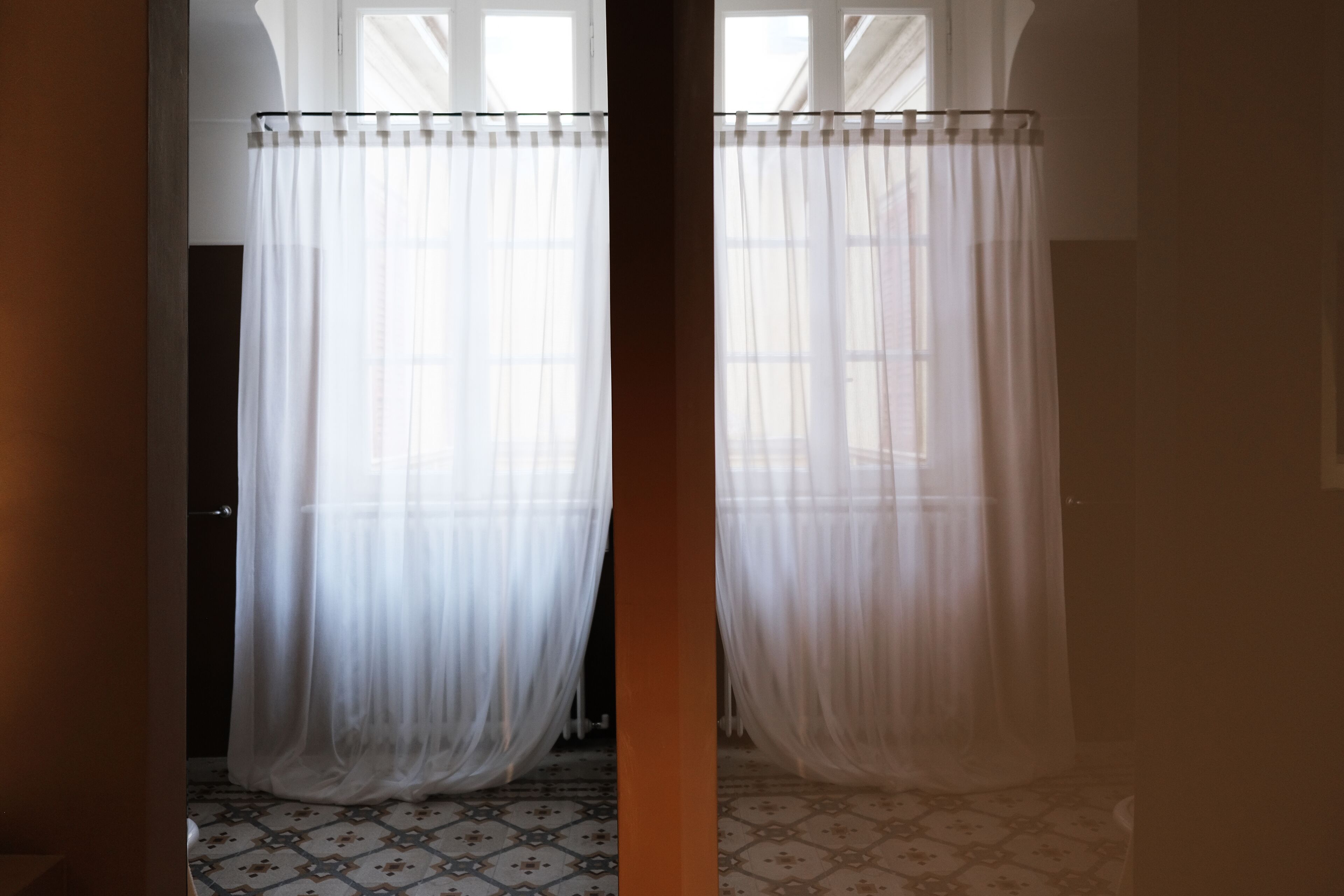 Una habitación con piso estampado, una cortina y un ventanal.