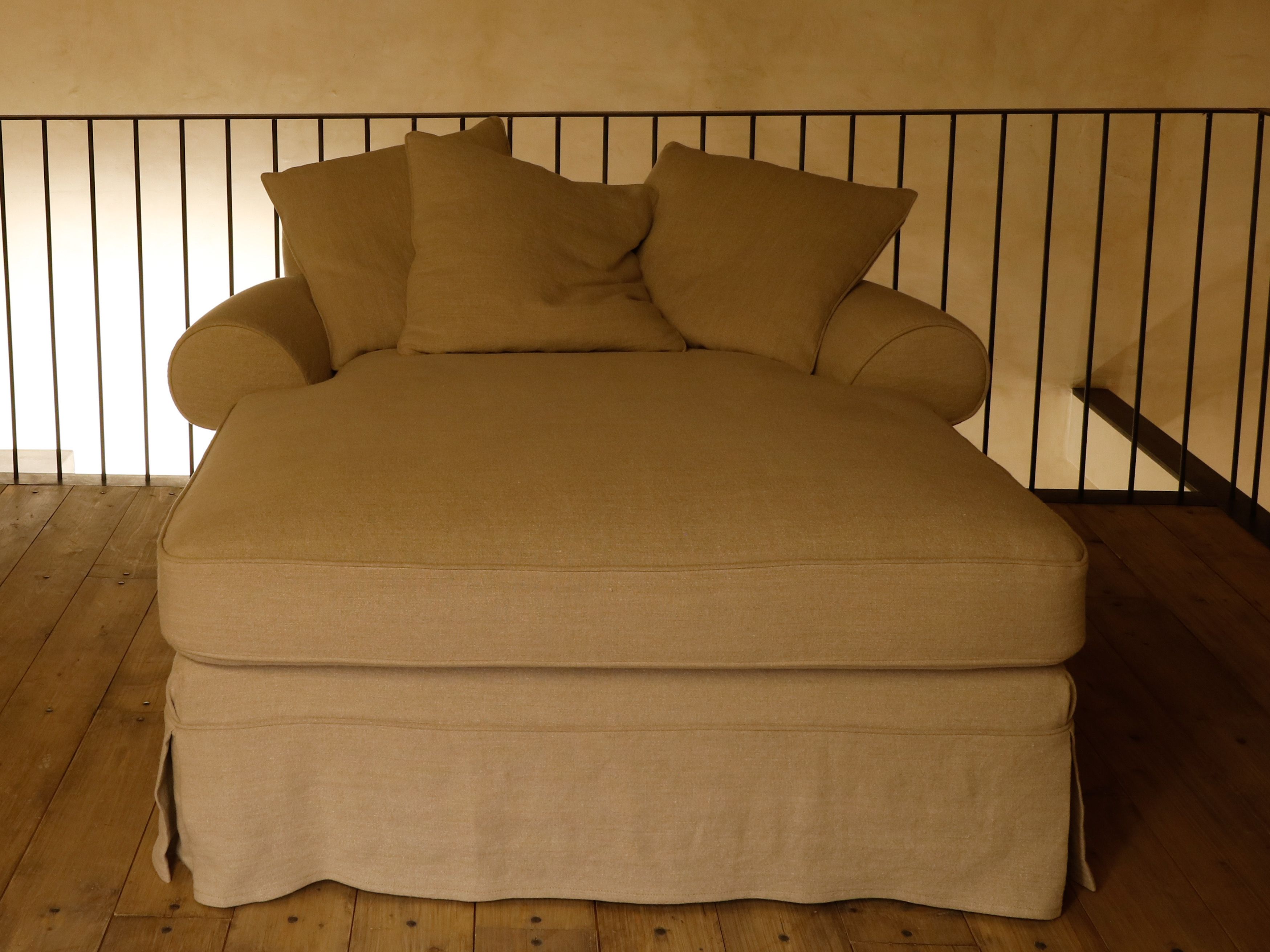 Una cama individual con cabecera apoyada en una pared, suelo de madera y pared lisa.