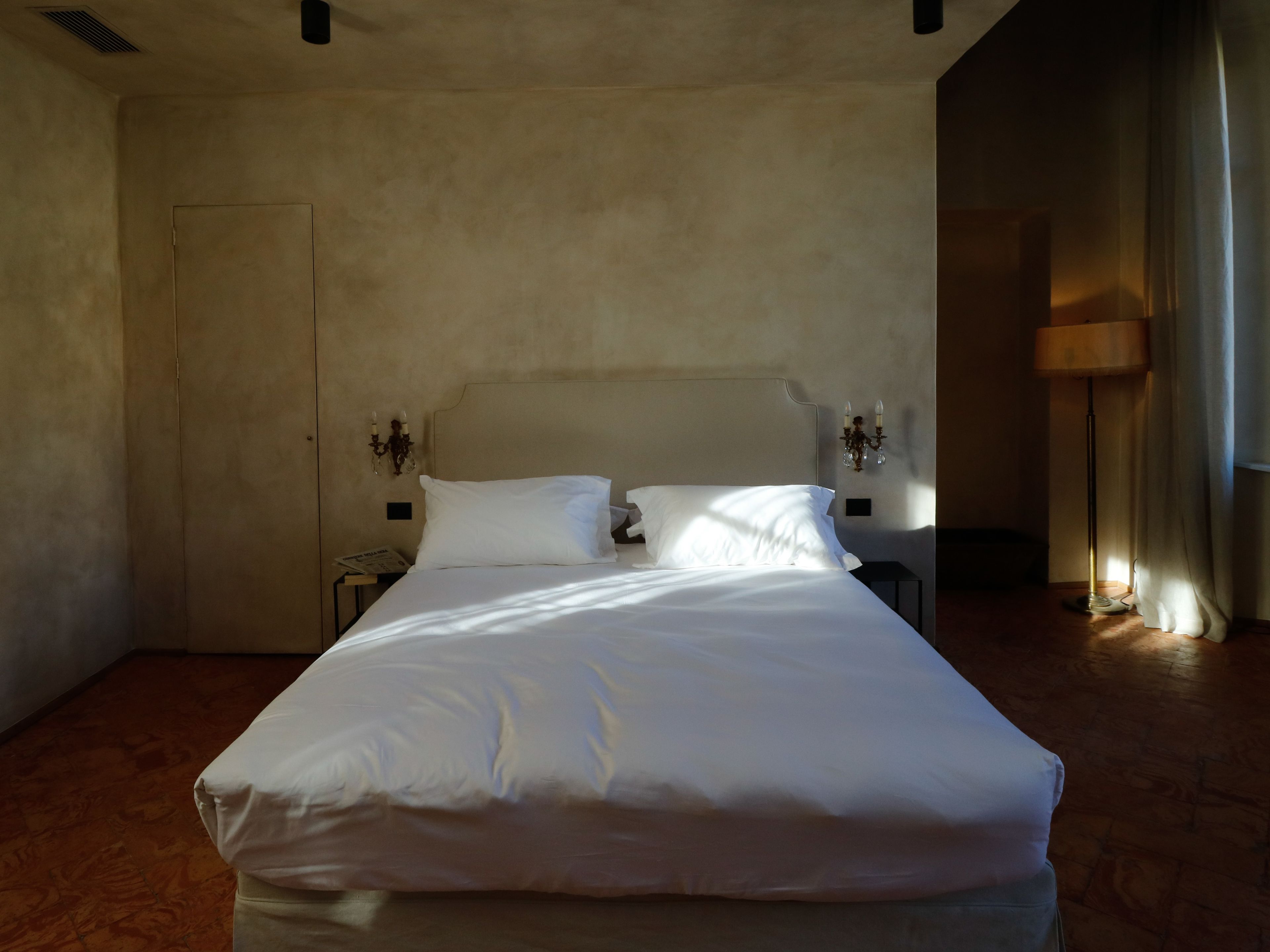 Una cama grande en una habitación con una pared lisa y una puerta.