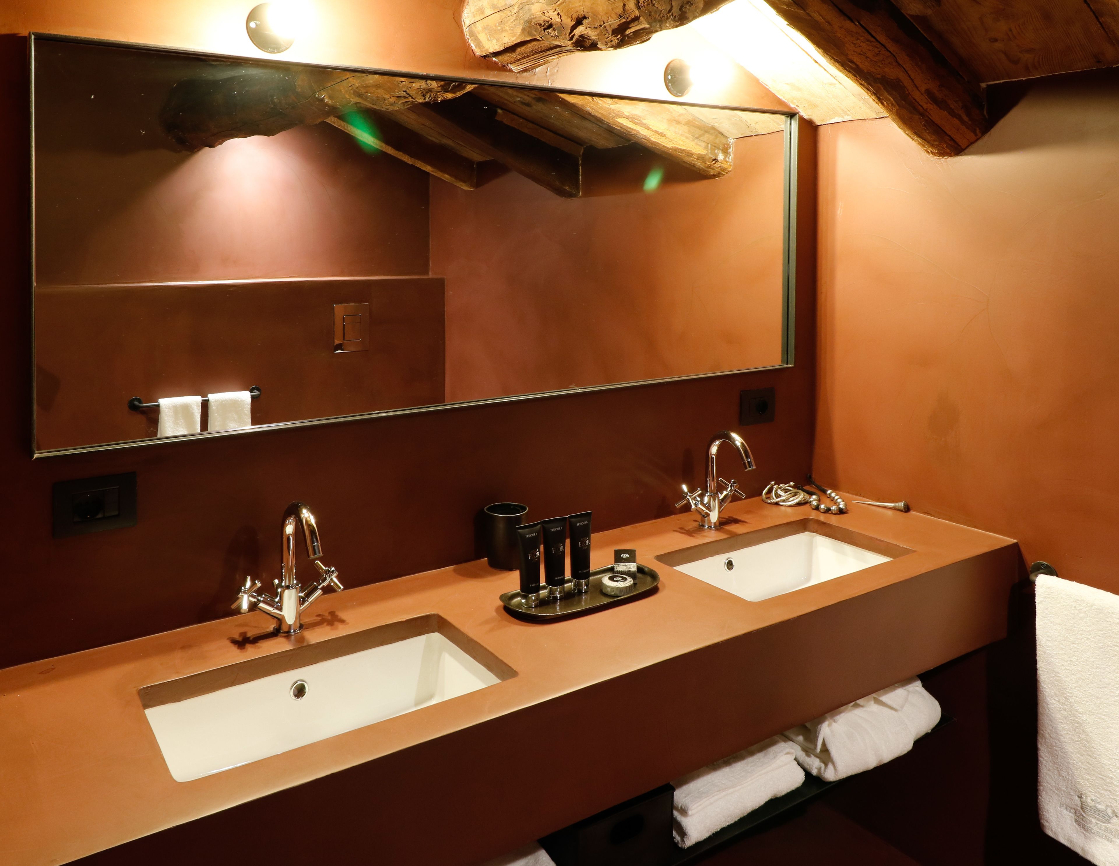 Un baño con dos lavamanos, un espejo grande y techo de madera.