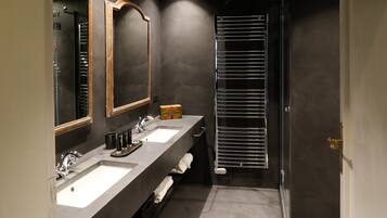 Un baño moderno con dos lavamanos, un espejo grande y un perchero para toallas.