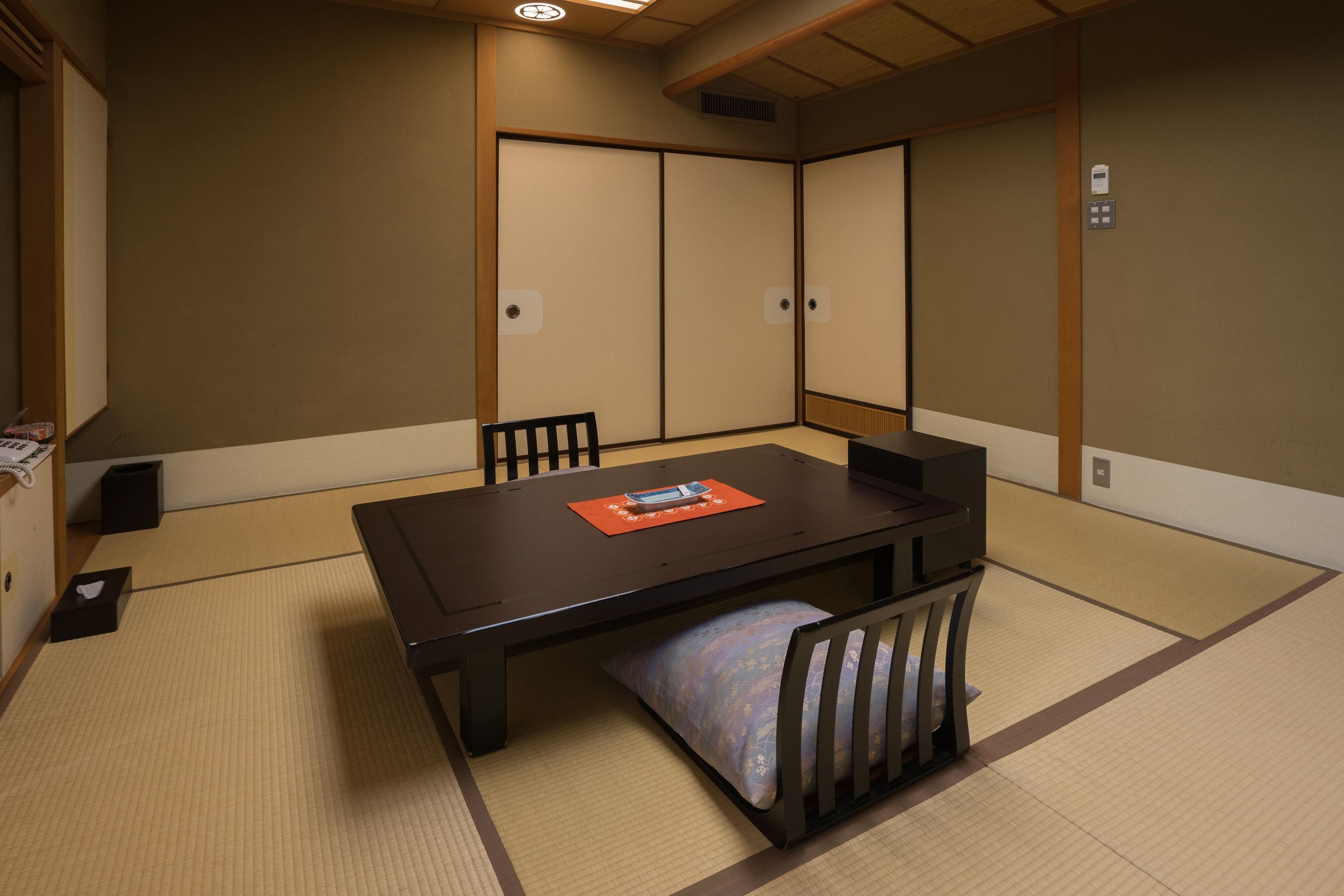 A traditional Japanese-style room with tatami flooring, a low table, and sliding shoji doors.